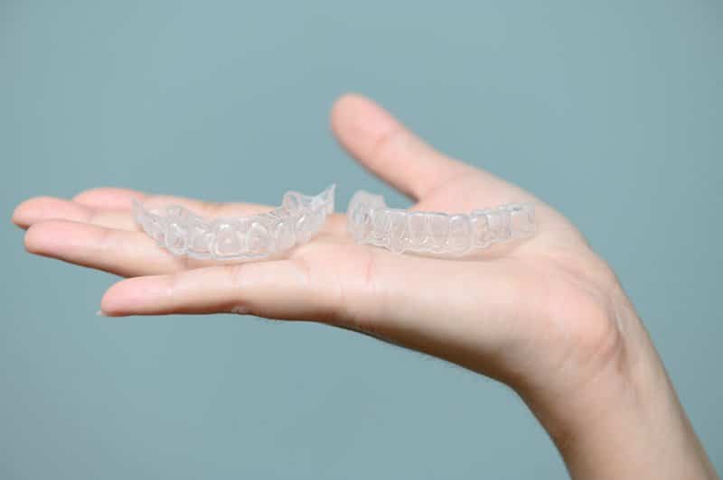 person holding Invisalign aligners